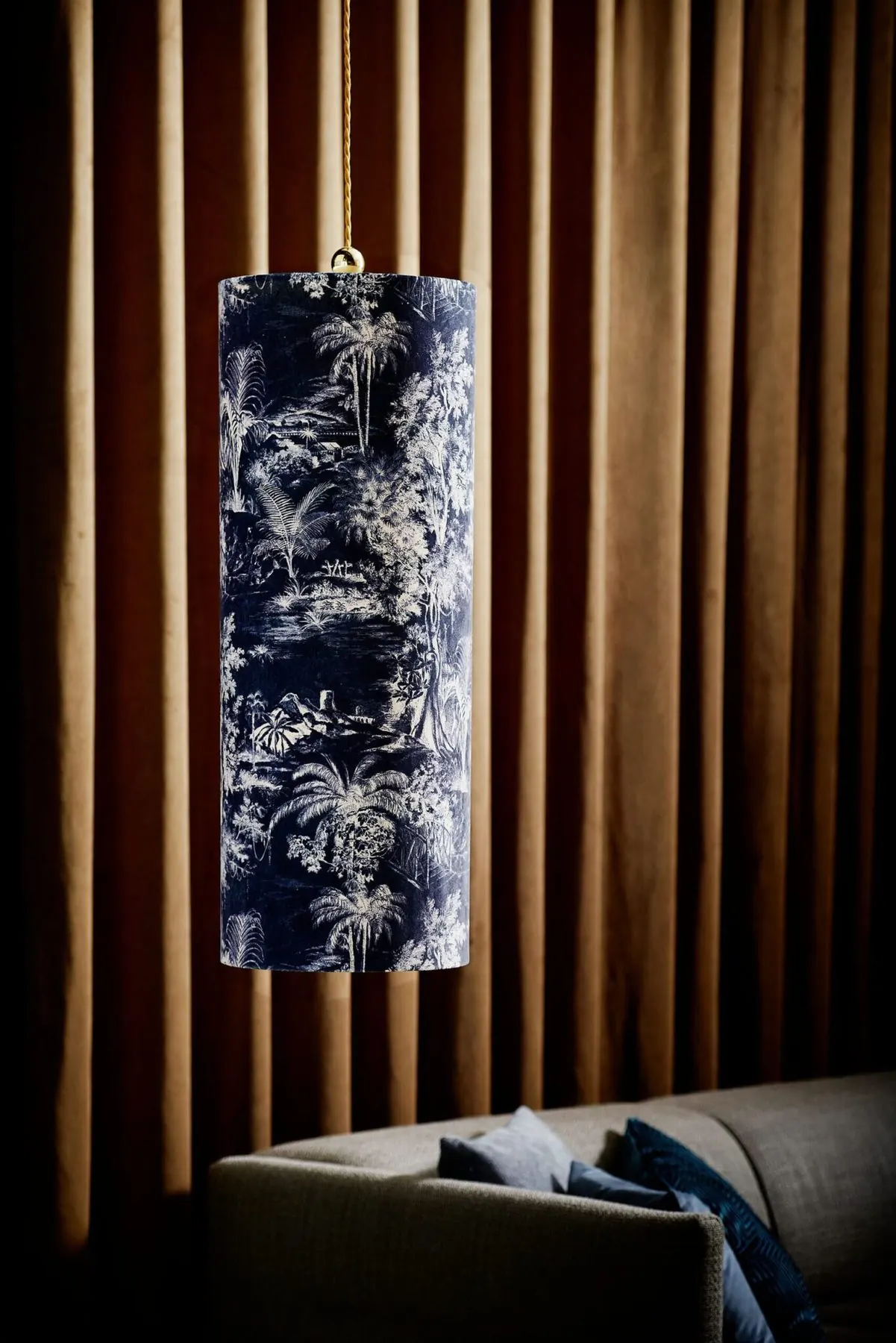 Pendelleuchte mit blau gemustertem Schirm vor einer Holzlamellenwand