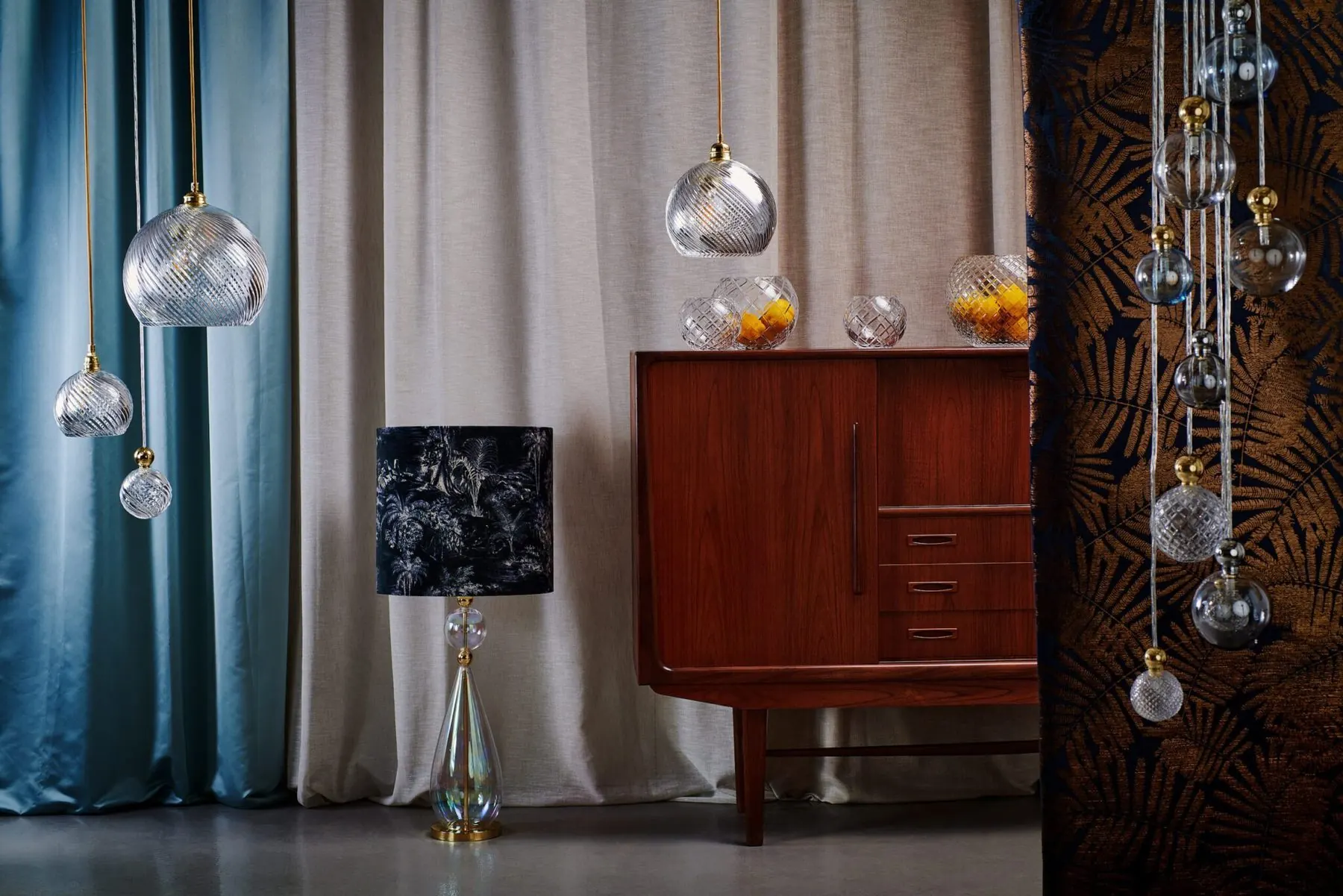 Pendel- und Tischleuchten über einem Sideboard vor blauen Vorhängen