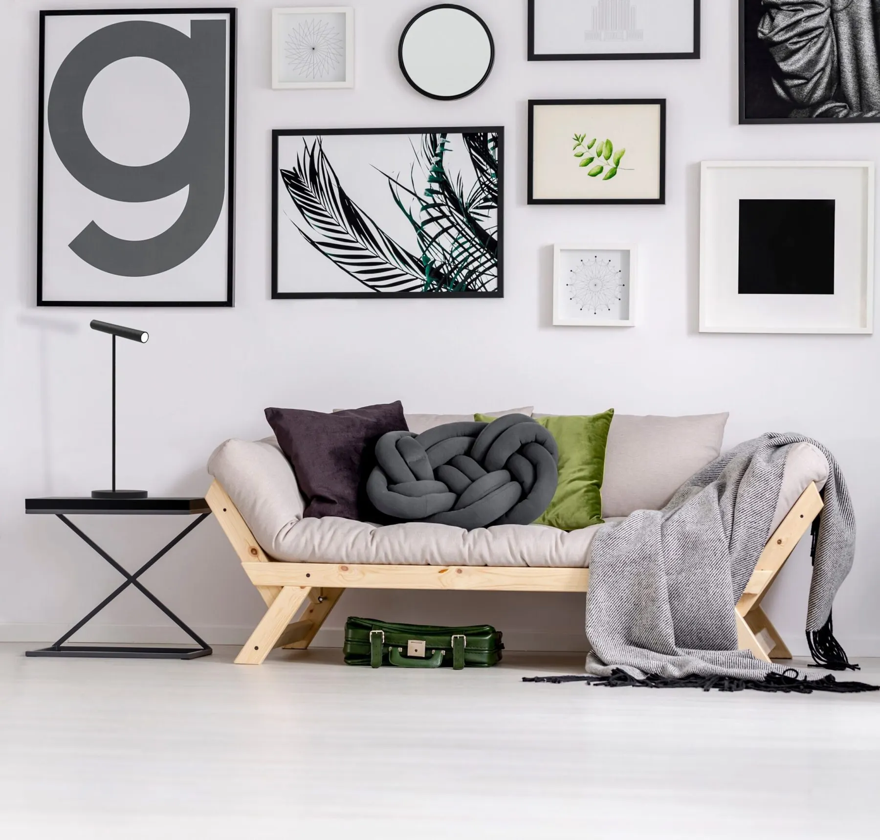 Tischleuchte Meyjo in Schwarz neben einem Sofa vor einer Bilderwand