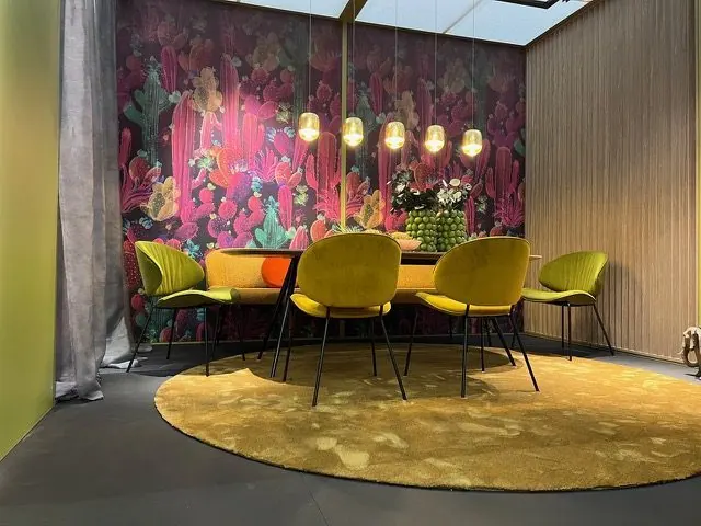 Sitzbank und Stühle unter Pendelleuchten vor einer floralen Tapete