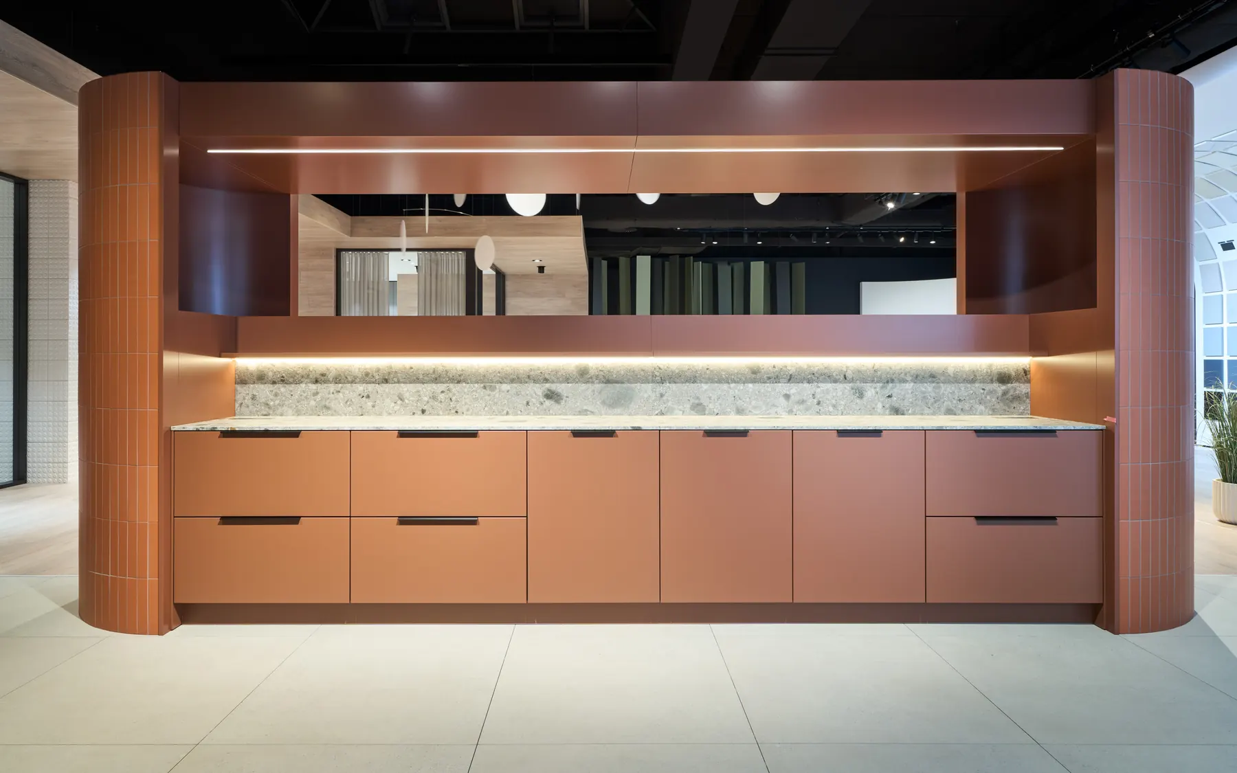 Küchenzeile in Terrakotta mit gerundeten Seitenwänden aus Riemchen und Arbeitsplatte aus Terrazzo