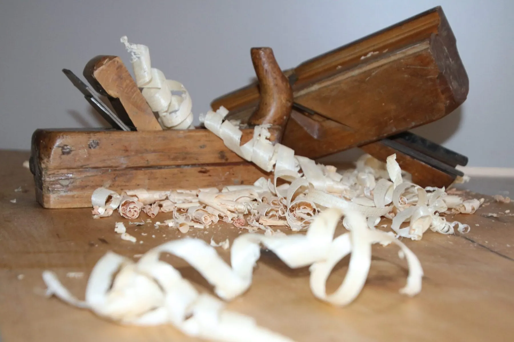 Alter Handhobel mit Holzspänen auf der Werkbank der Tischlerei
