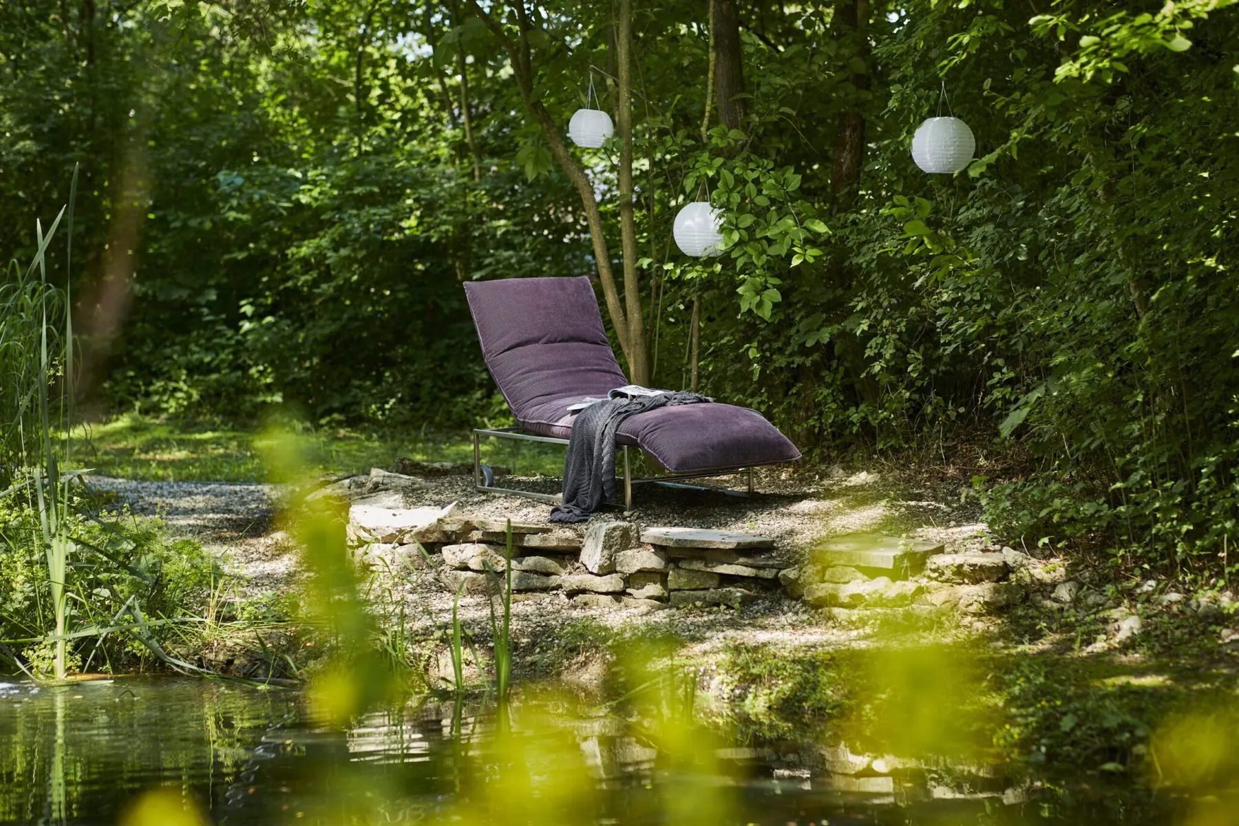 Outdoor-Liege Lettino am Ufer eines Gartenteichs