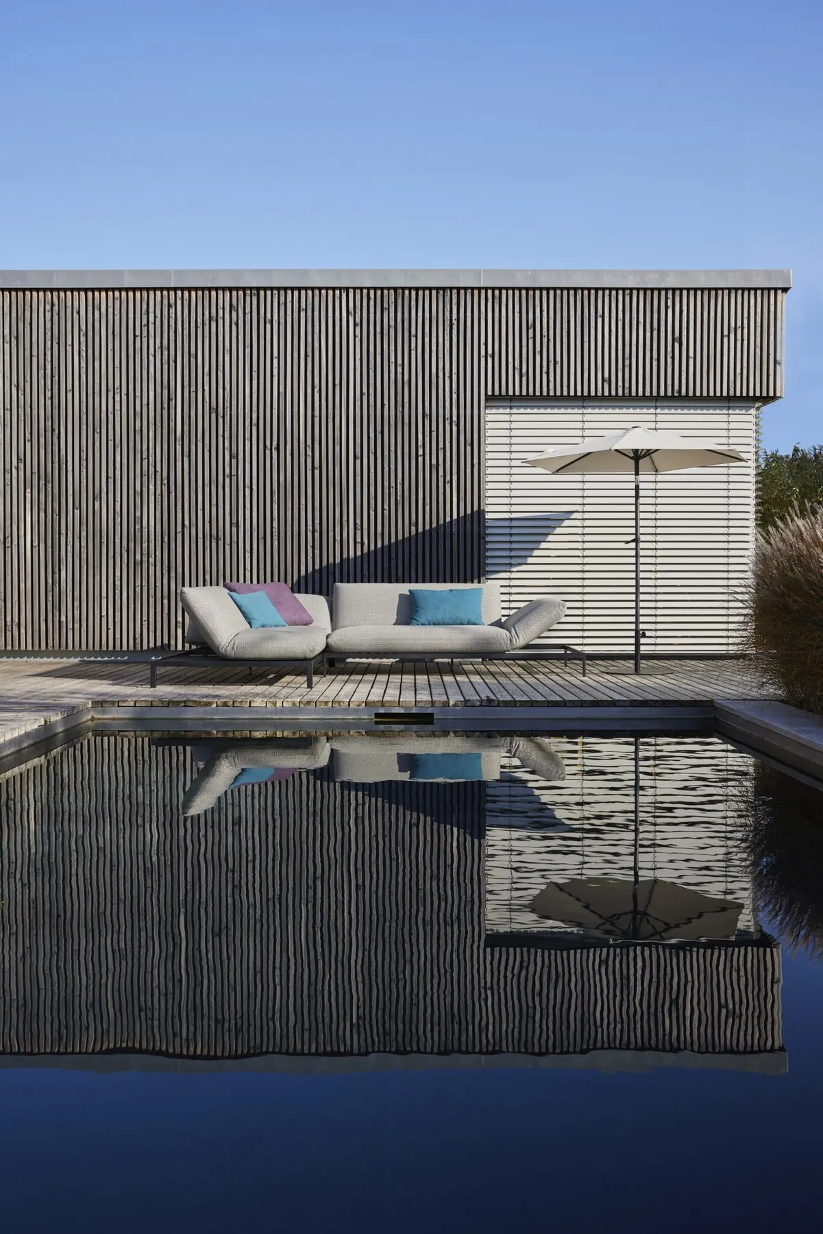 Outdoor-Serie Kaya mit Sonnenschirm am Rand eines Pools
