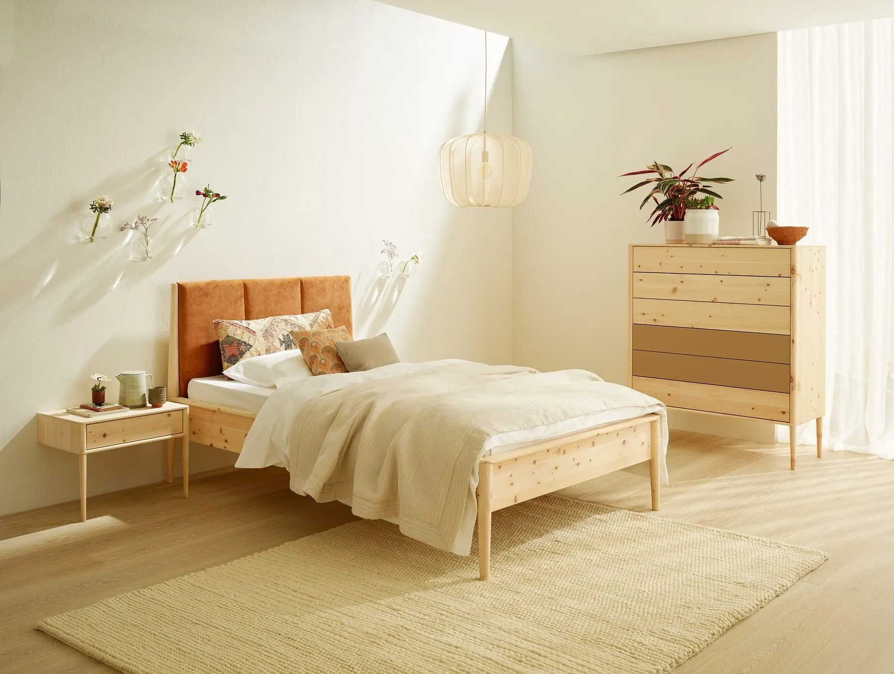 Schlafzimmer mit Massivholzbett, Nachtkästchen und schmaler Kommode