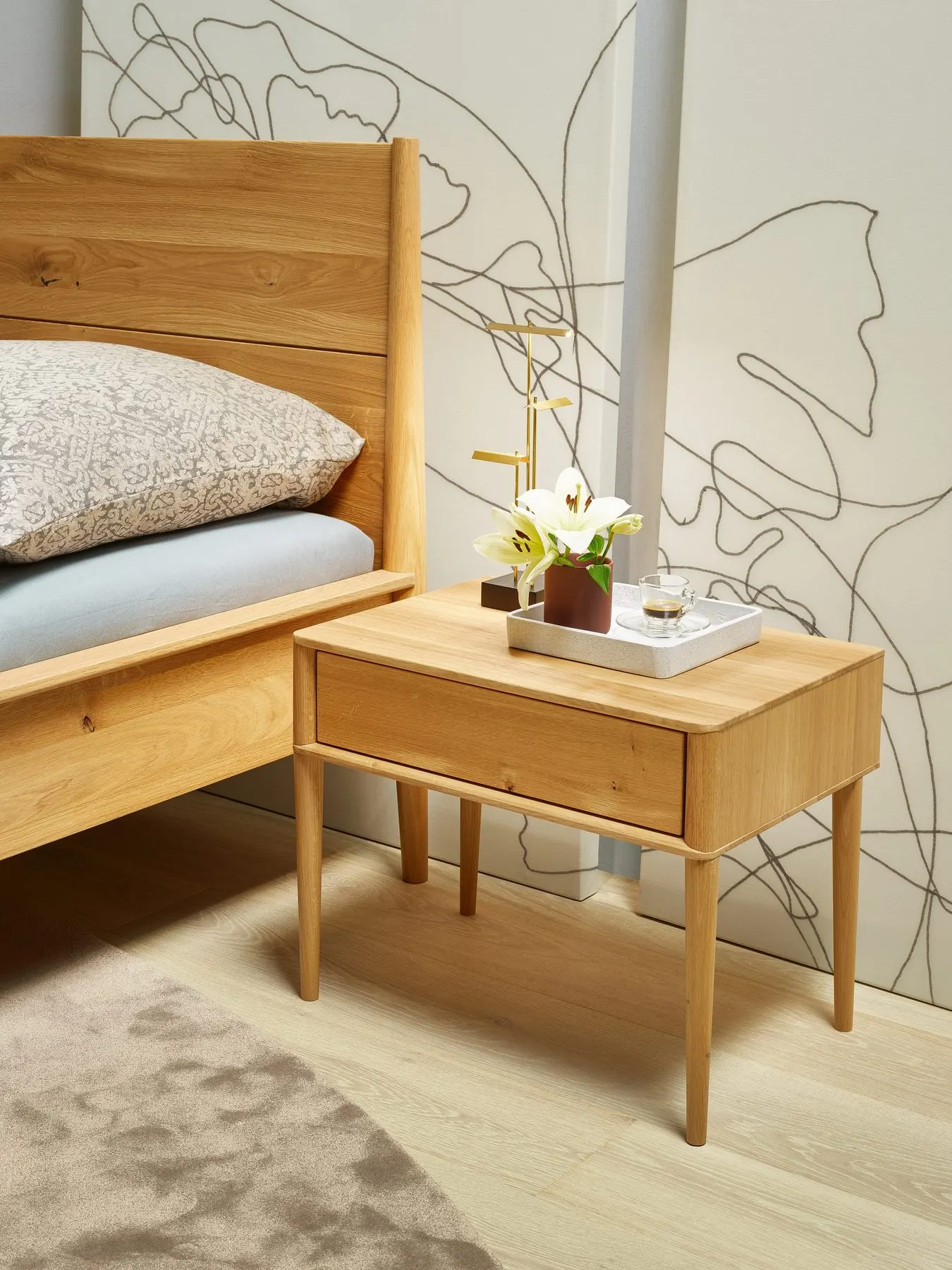 Nachtkästchen und Bett mit Wandzeichnung unter einer Dachschräge