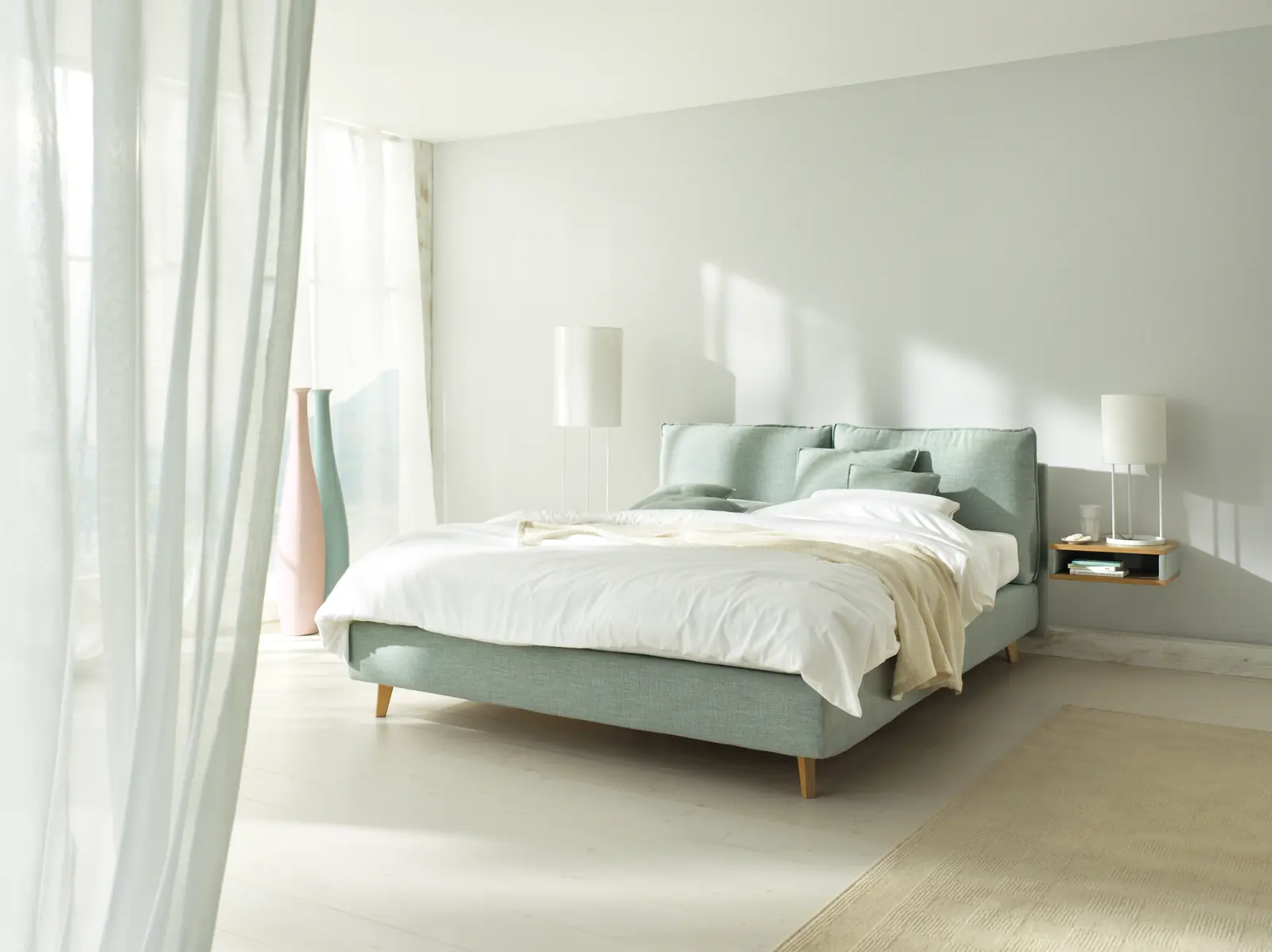 Mintgrünes Boxspringbett Arte mit filigranen Füßen in einem hellen Schlafzimmer