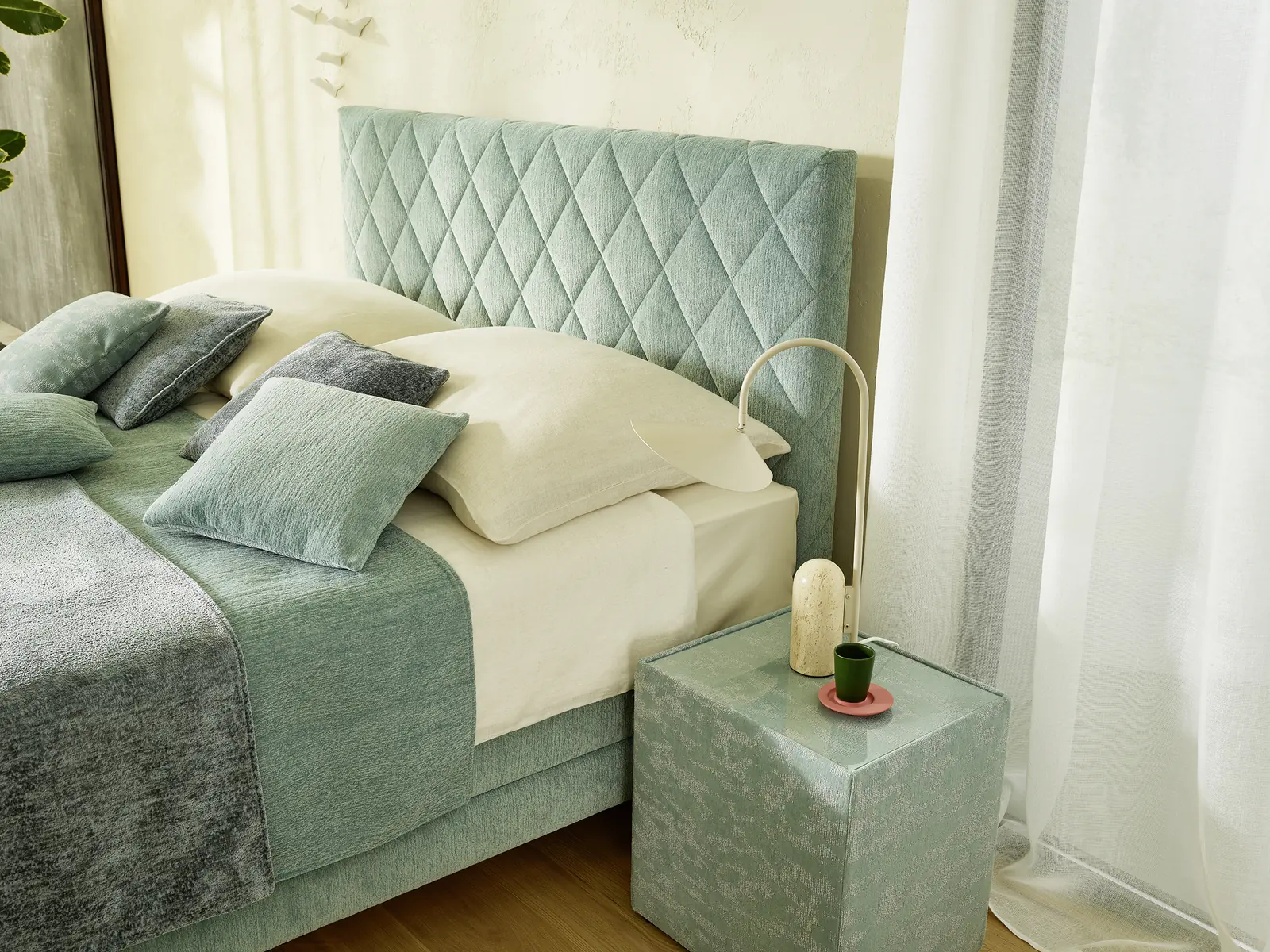 Boxspringbett mit rautenförmig abgestepptem Kopfteil und grüner Tagesdecke