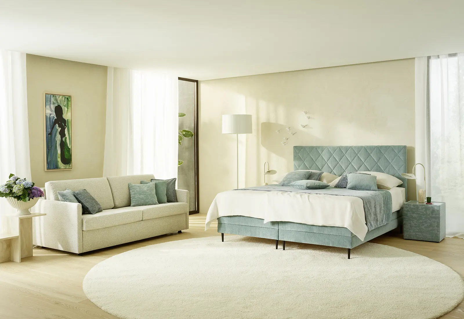 Mintgrünes Boxspringbett mit gepolstertem Kopfteil und Sofa im Schlafzimmer