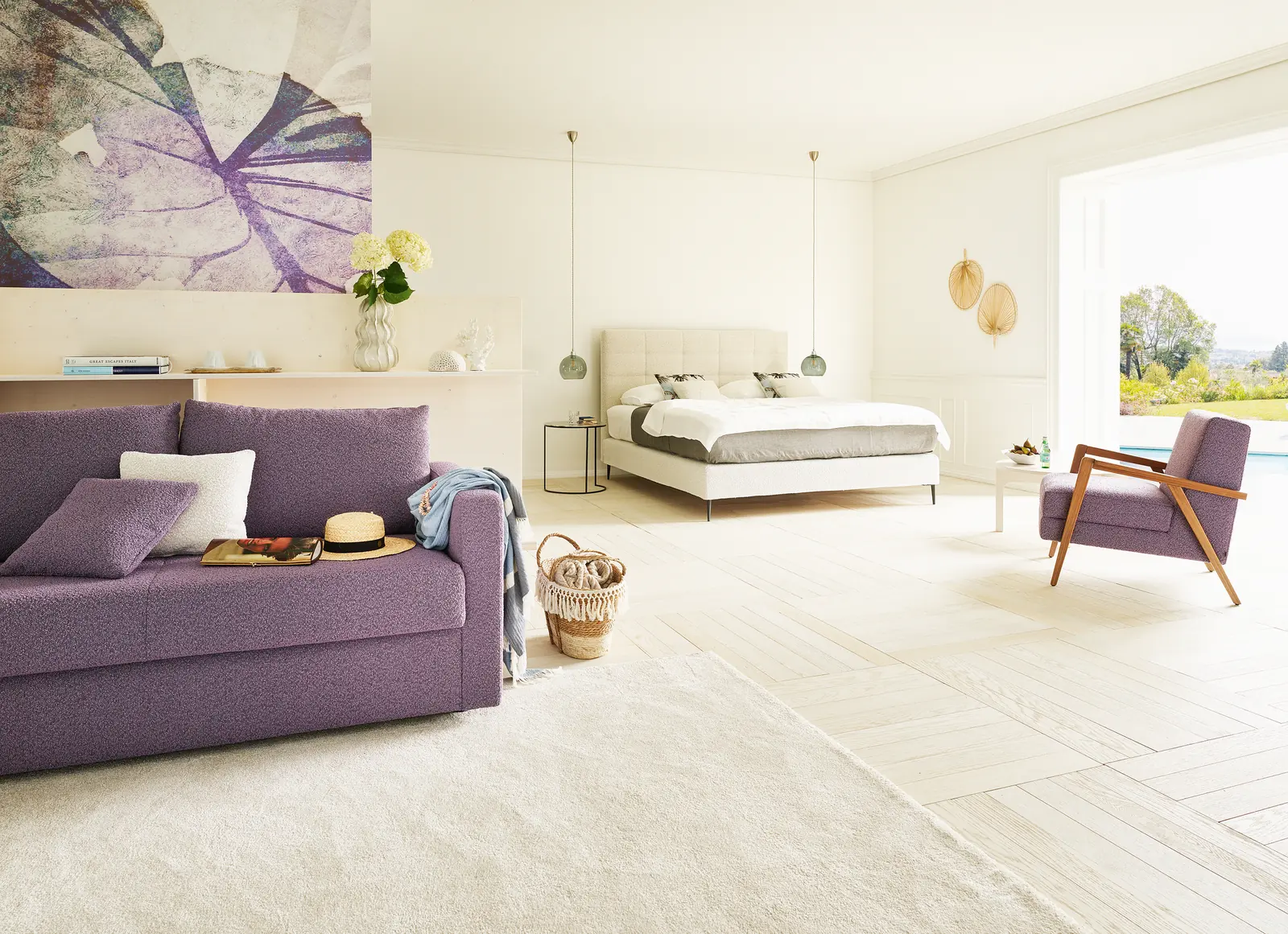 Boxspringbett Mattina neben einem violetten Sessel und Beistelltisch im Schlafzimmer