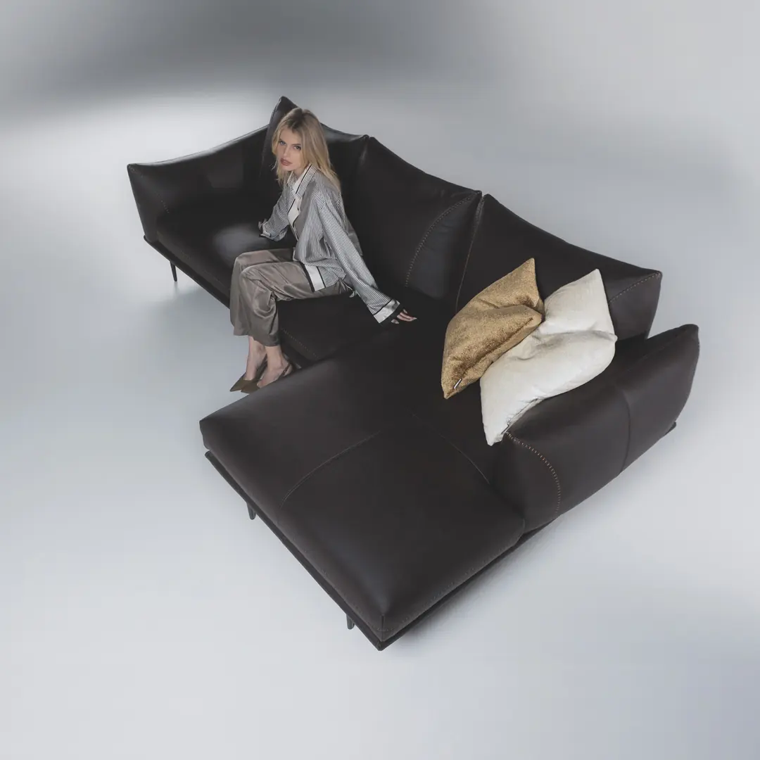 Person auf einem schwarzen Sofa Dragees mit hellen Kissen