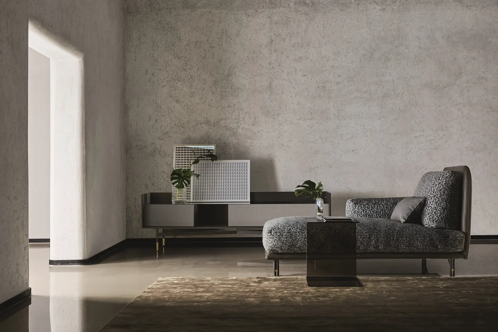 Gepolstertes Sofa Kris Mix vor einer Betonwand mit Tischleuchte