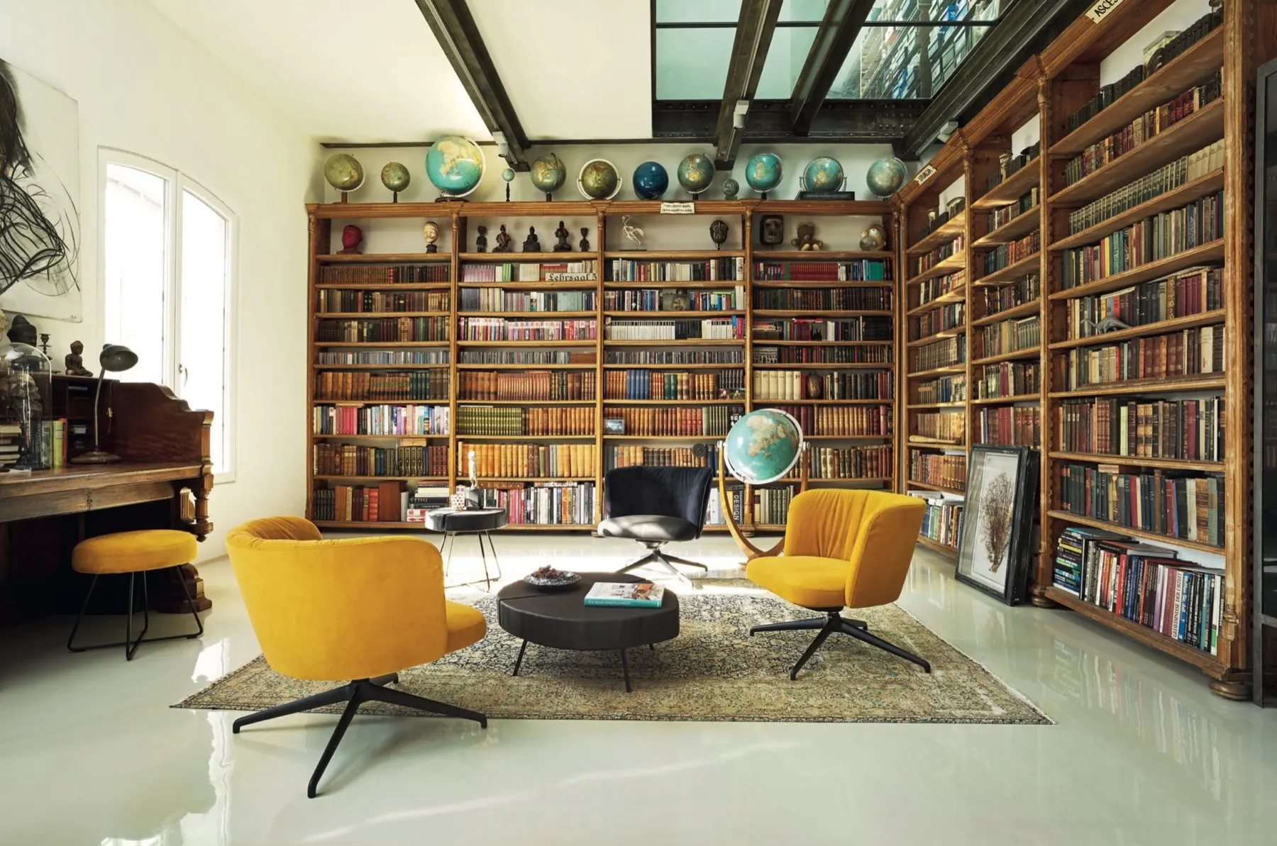 Raumhohe Bibliothekswand mit Büchern und gelben Drehsesseln