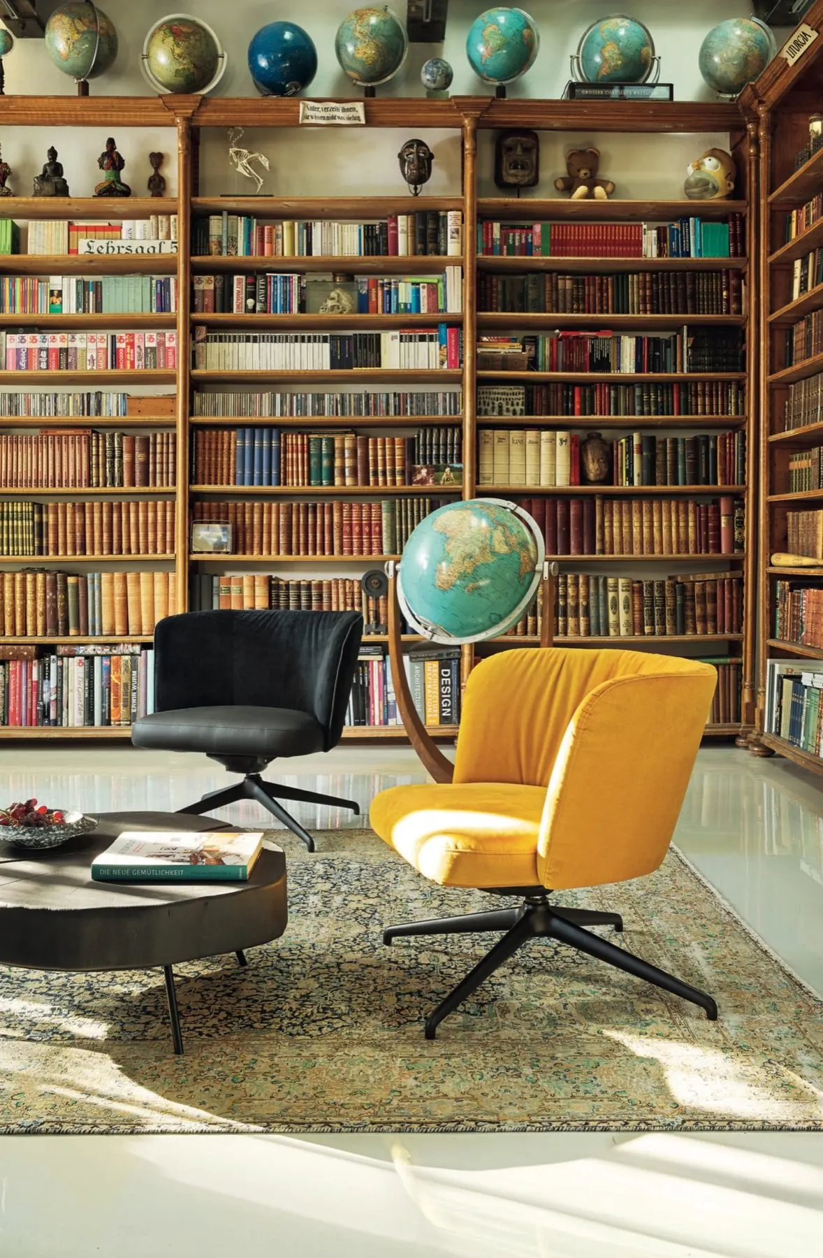 Bücherregal mit Sammlerstücken und gelbem Drehsessel
